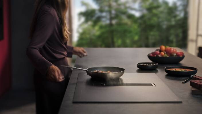 Ženska pripravlja jed v ponvi na kuhalni plošči AEG SaphirMatt